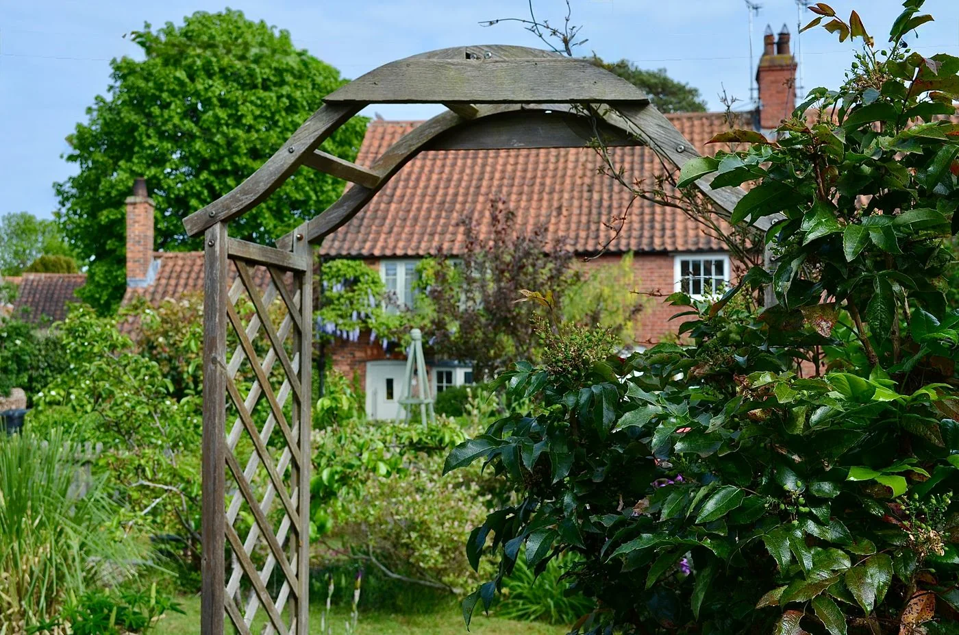 Timber garden arch surrounded by lush planting in an English cottage garden
